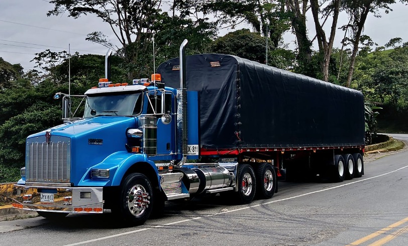Tractomula Kenworth azul con carpa en carretera nacional